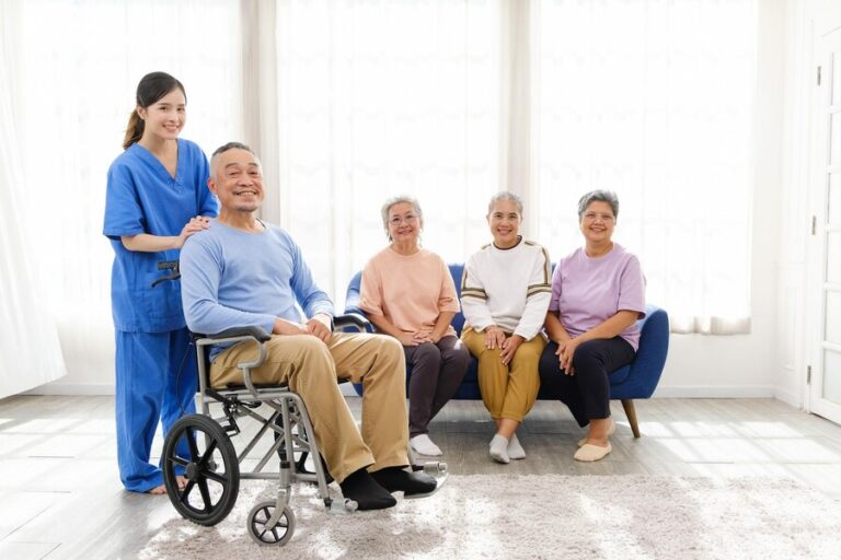 caregiver-therapist-stands-with-asian-senior-sitting-wheelchair-with-group-senior-women-sitting-sofa-background-nursing-home-facilitates-support-group_43263-3586